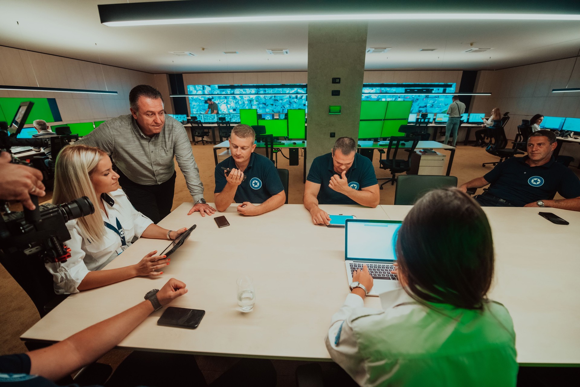 Group of security guards sitting and having briefing In the system control room They're working in security data center surrounded by multiple Screens